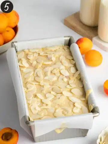 apricot cake with sliced almonds in a cake pan before baking.