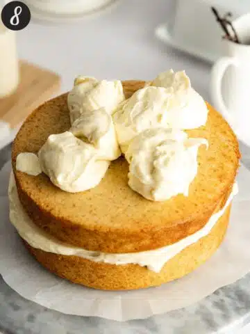 a vanilla sandwich cake with frosting dolloped on top.