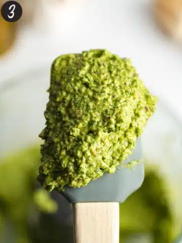 a spatula with green pesto on it showing the thick consistency.