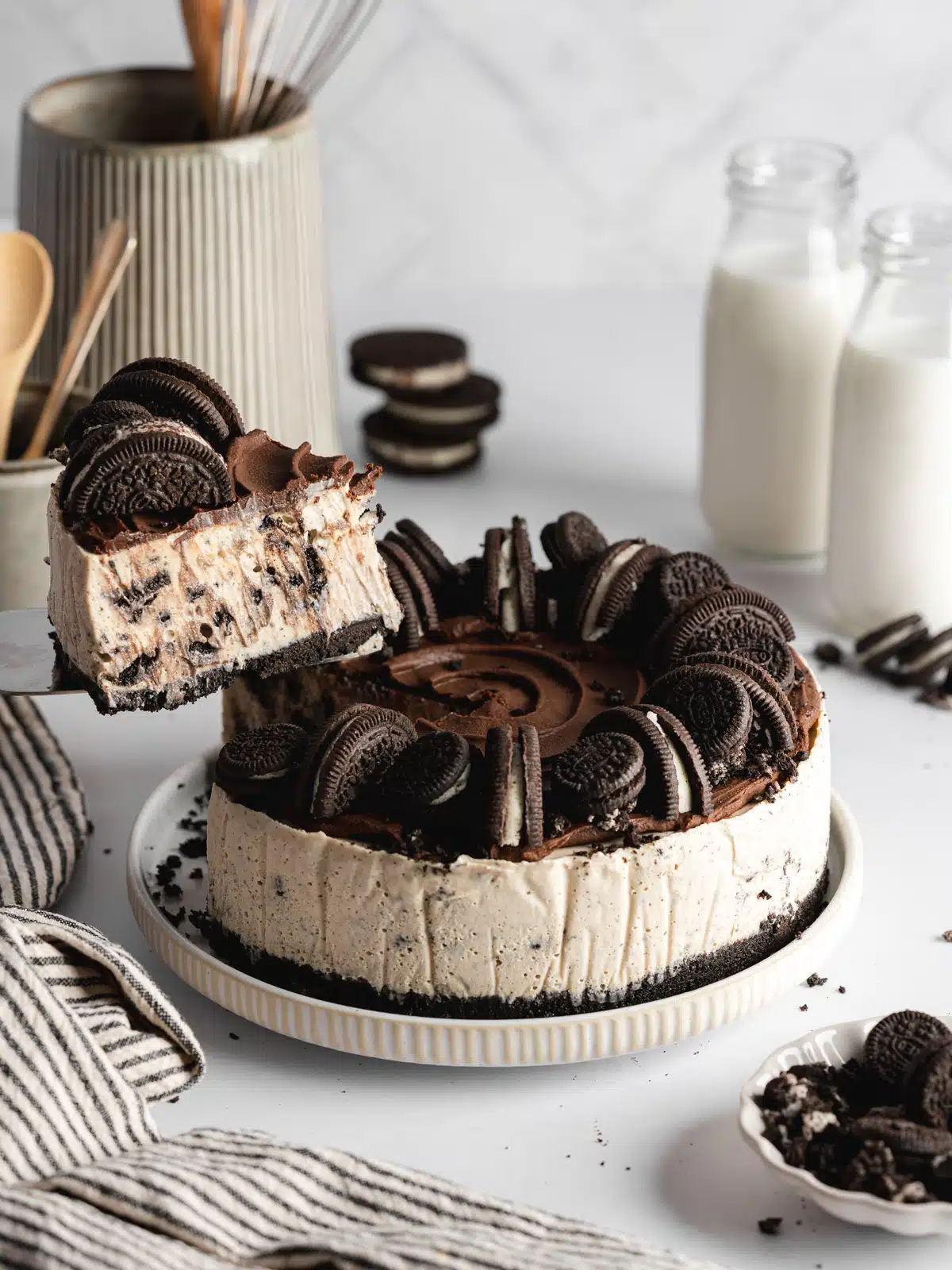 a full oreo cheesecake with a slice being lifted away on a cake slice, showing the creamy interior.