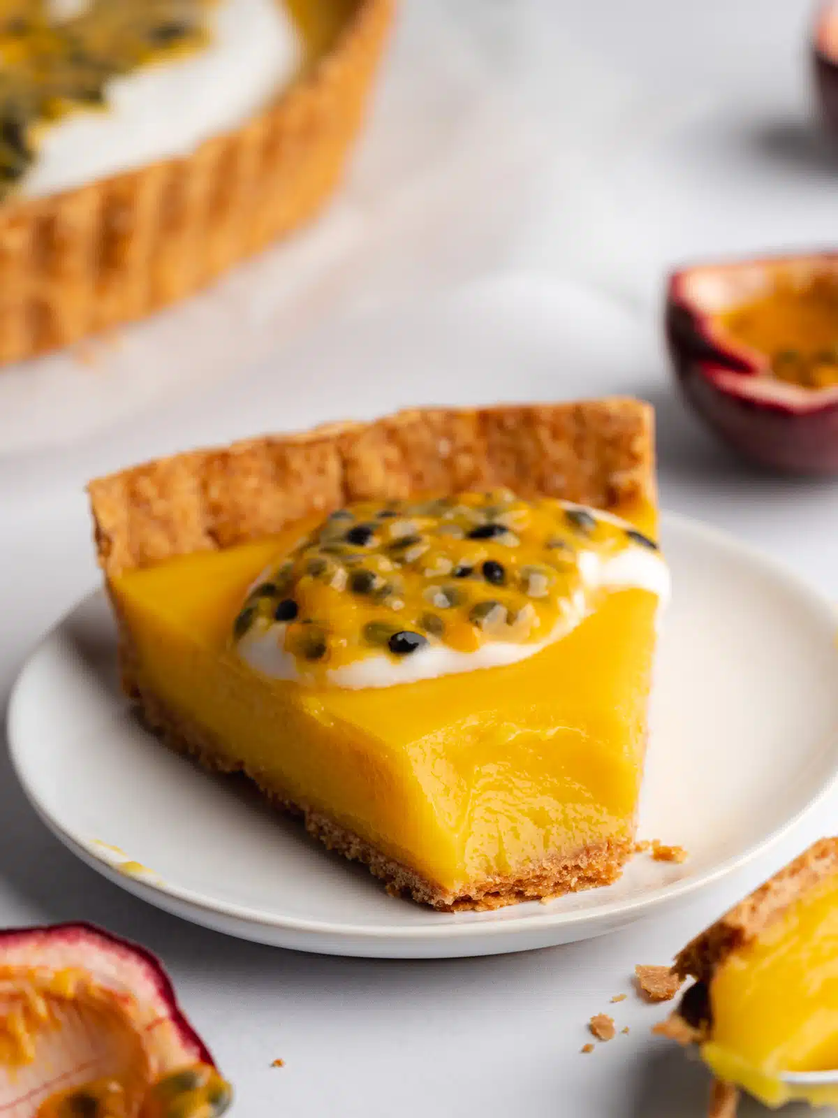 a slice of passionfruit tart on a white plate topped with fresh passion fruit puree.