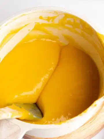 thickened passionfruit curd in a saucepan with a spatula showing the thick consistency.