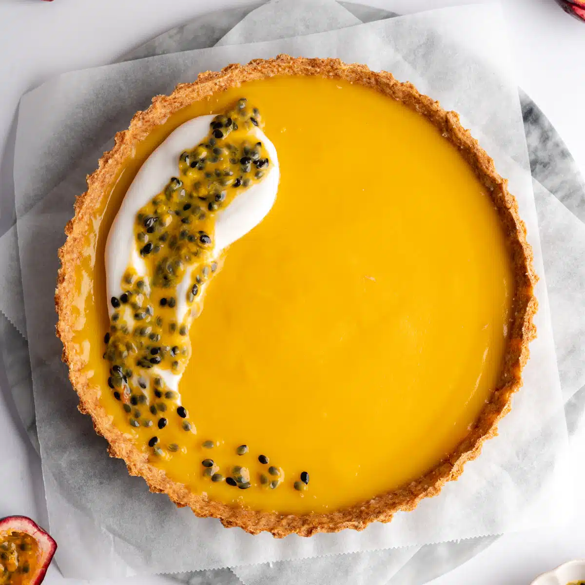a passion fruit curd filled tart with a dollop of coconut cream and fresh passionfruit on top.