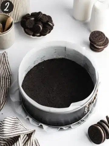 oreo cookie crust pressed into the base of a springform cake pan lined with parchment paper.