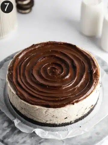 chocolate ganache topping swirled on top of a set oreo cheesecake.