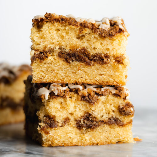 2 slices of vegan coffee cake stacked on top of eachother showing the cinnamon streusel swirl and thick layer of crumb topping.