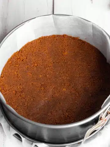 biscoff cookie crust compacted into the base of a springform pan lined with parchment.