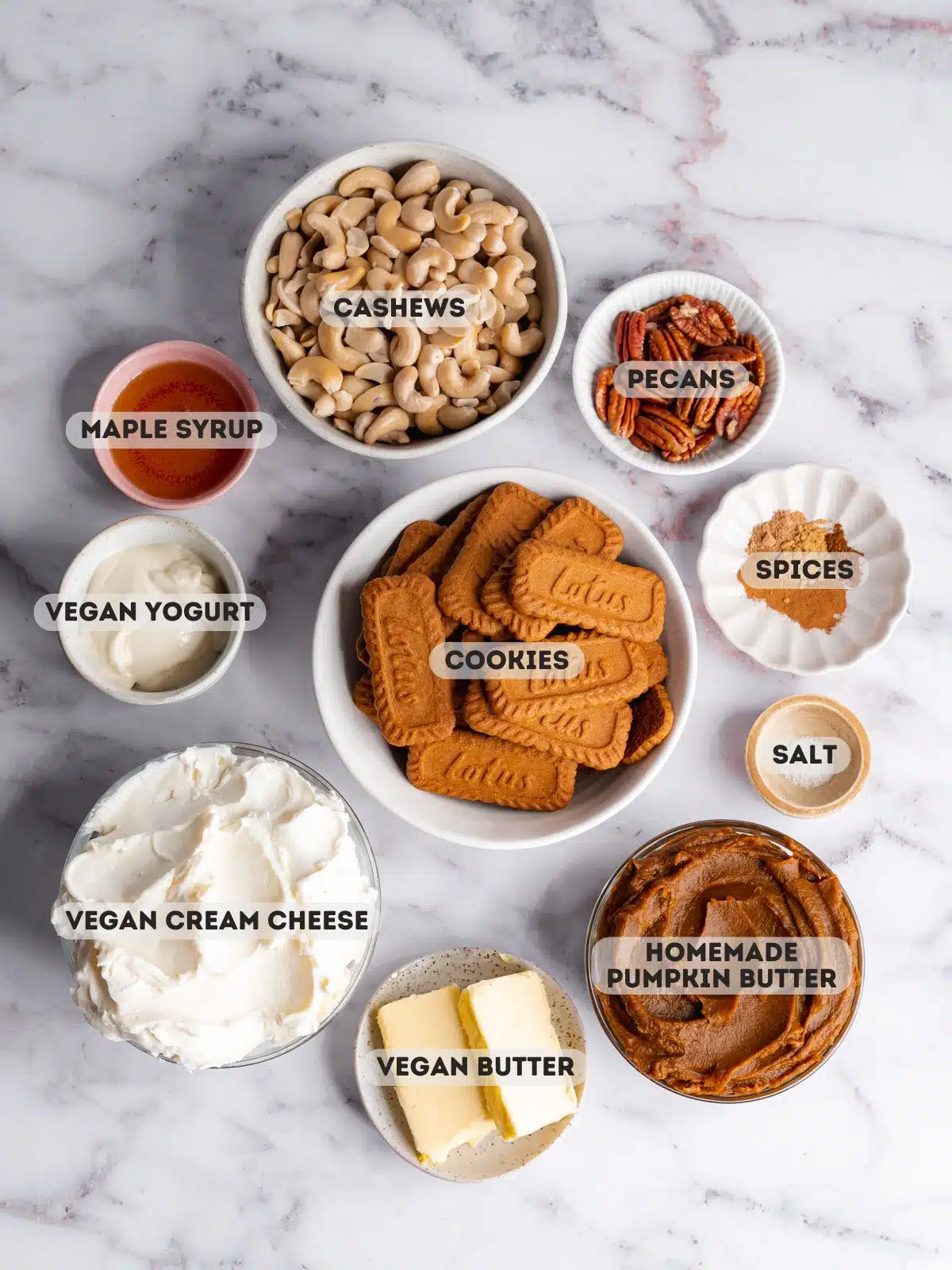 ingredients for vegan pumpkin cheesecake measured out in bowls on a marble surface.