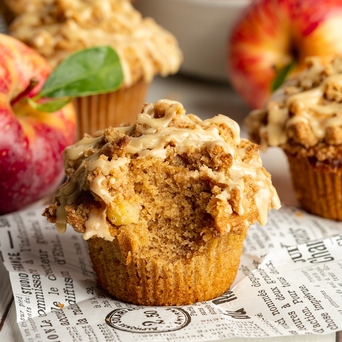 apple muffin with streusel topping and a bite taken out of it showing the fluffy interior.